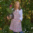 Model wearing Bohemian Floral Moss Green & Mauve Pink apron and holding flowers