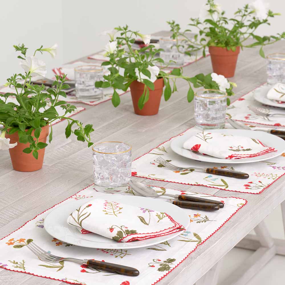 Dinner table with linen placemat and linen napkin and greenery. 