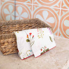 Floral linen cocktail napkin draped over a wicker basket. 