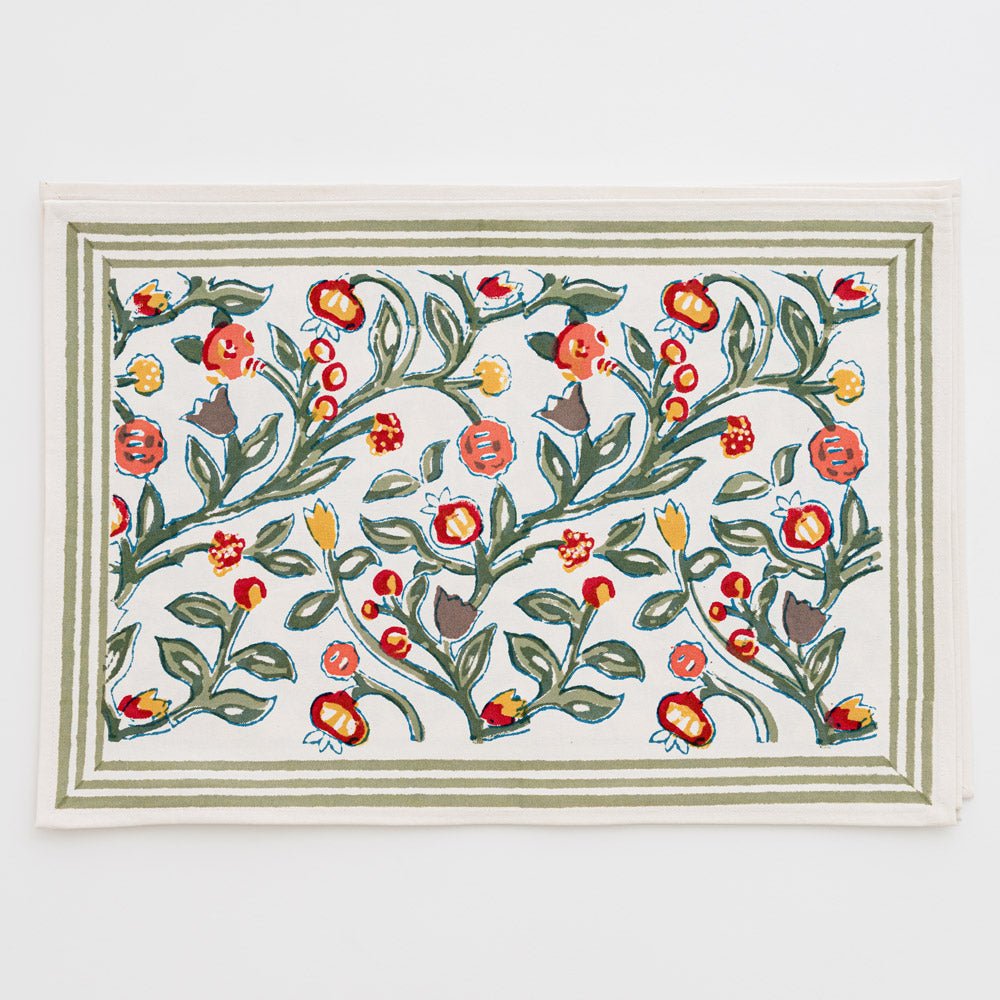 stack of placemats printed with green vines and floral buds in shades of crimson, marigold, and deep orange on white background