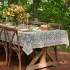 tablecloth with floral pattern in shades of sage green, crimson, marigold and deep orange on a table outdoors