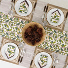 Pinecones in basket in middle of table runner. 