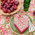 Spice Route Garnet Red Napkin with pomegranate fruit and green plates.