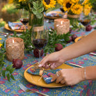 Model laying Cactus Flower Midnight Dark Blue & Magenta Floral napkin on yellow plate