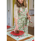 model wearing emma red & green floral apron setting table with matching placemats