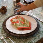 Harvest Pinecone Orange & Green Napkin on white plate with dark brown charger