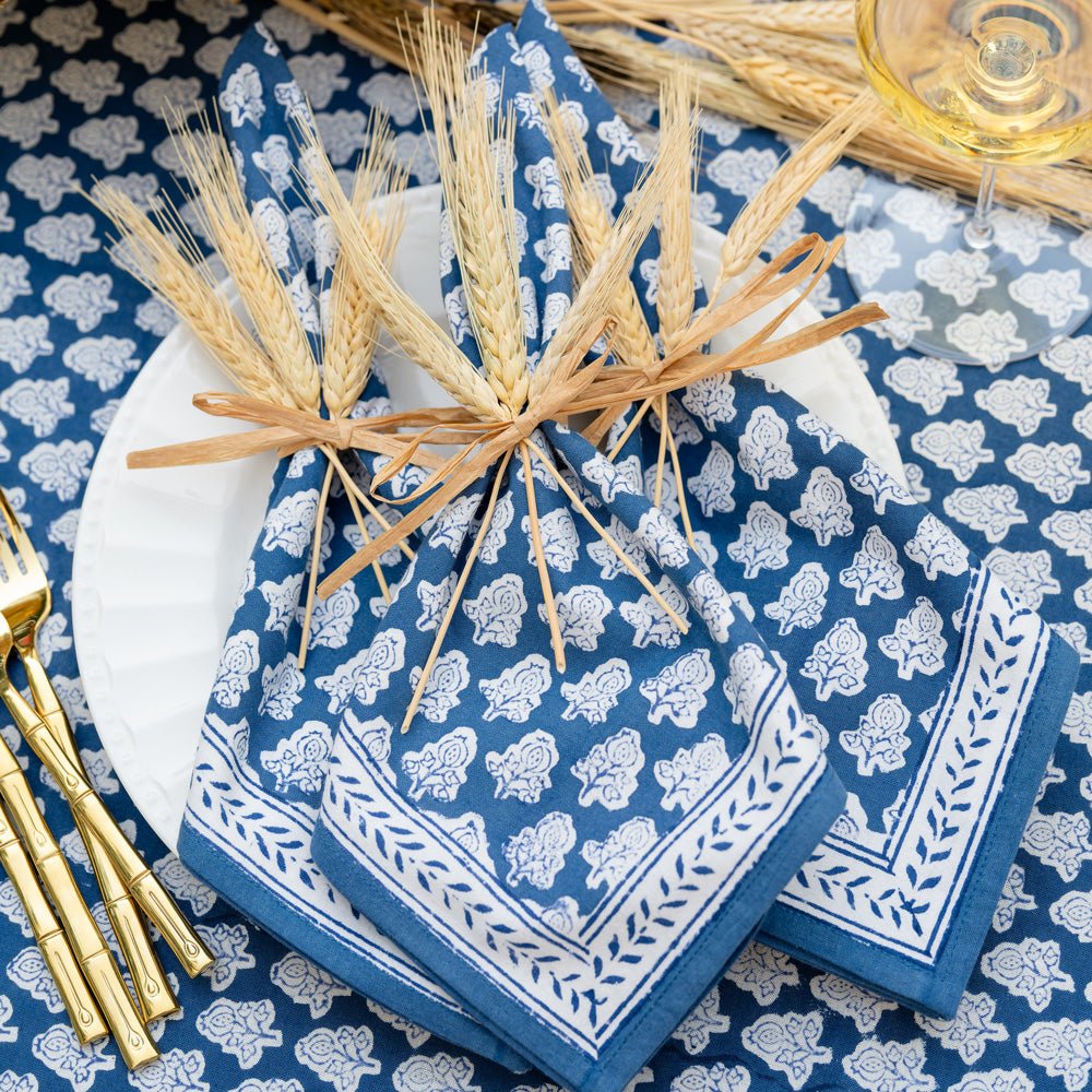 Pom buti denim napkins on white plate tied with wheat