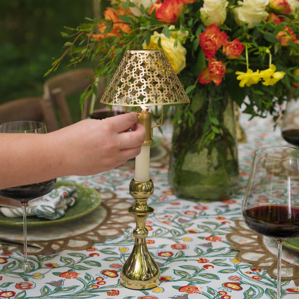 gold candlestick and cutwork shade being lit with match