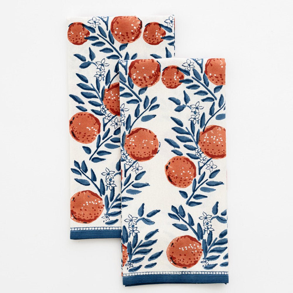 two tea towels printed with oranges and blue floral design on white background