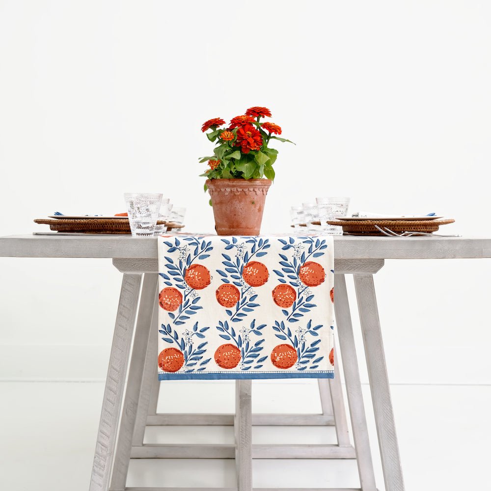 grey table with orange grove table runner with blue vines and oranges on a white background