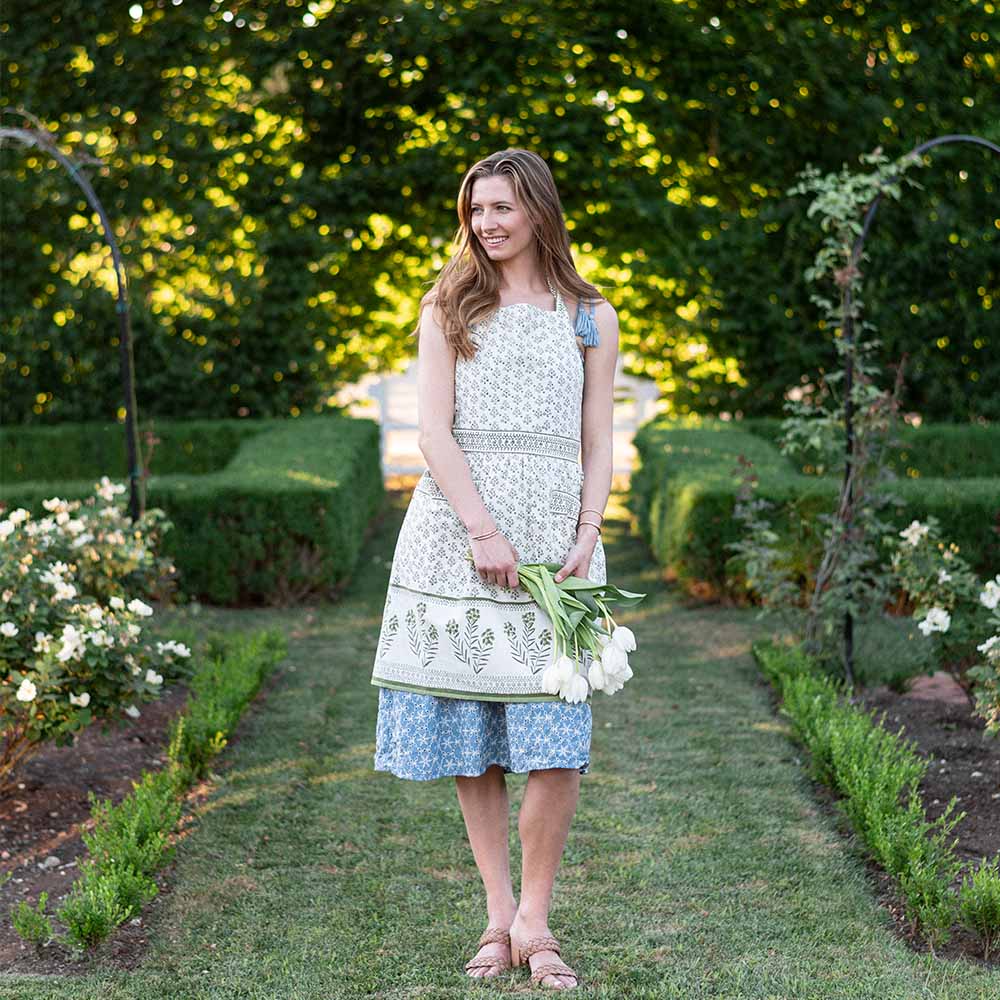 Model wearing apron and holding flowers. 