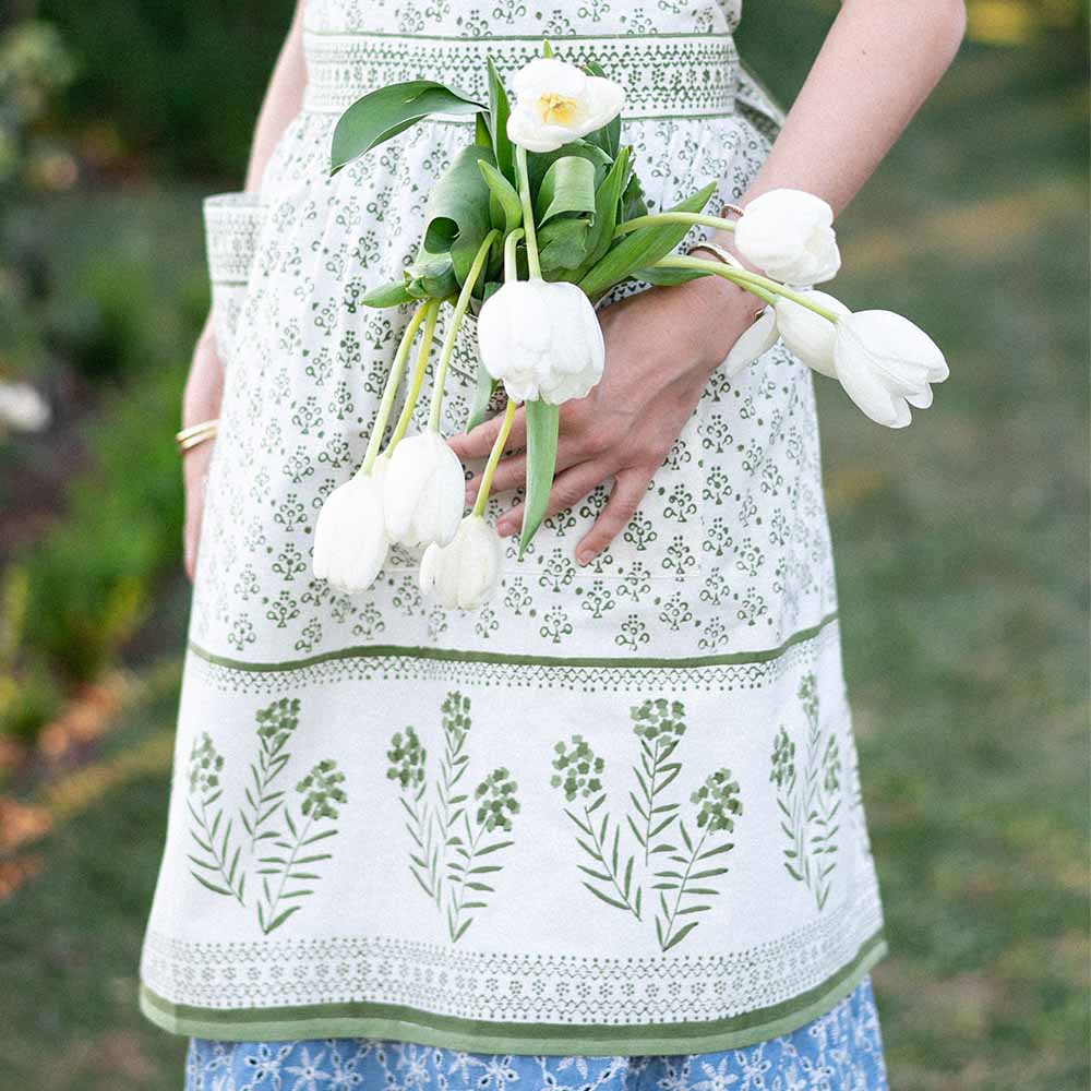 Model wearing apron and holding flowers. 